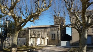 Una proprietà rurale con un vialetto sterrato che conduce a un edificio in pietra con tetto in tegole.