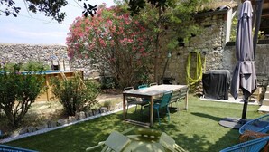 Un cortile con un tavolo rotondo e sedie, un'area barbecue e un muro in pietra.