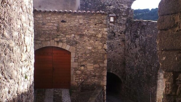 Un edificio in pietra con una porta in legno e un cortile in pietra.