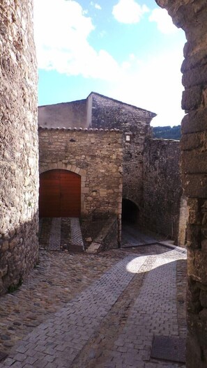 A stone building with a wooden door and a cobblestone courtyard. - Clos Saint Roch family home (Viviers)