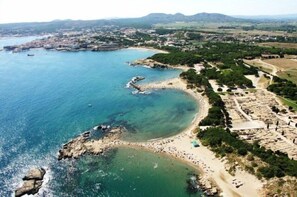 Vista aérea de uma cidade costeira com praia, falésias rochosas e áreas residenciais.