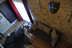 A rustic room with a stone wall, wooden floor, and a bed with pillows.