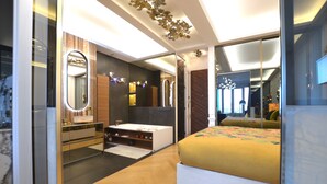 Une chambre à coucher moderne avec un grand lit, une coiffeuse avec un miroir, une baignoire intégrée et un plancher en bois.