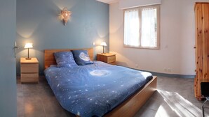 Un dormitorio con una cama, dos mesitas de noche, una cómoda, una ventana y un armario.