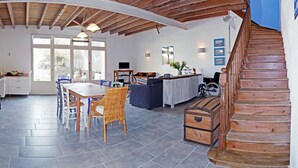 Una cocina amplia con comedor, escalera de madera y vistas a través de ventanas grandes.