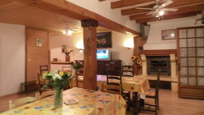 Ein Essbereich mit Holzbalken, Kamin und Fernseher.
