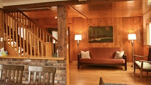 A wooden interior with a staircase, a sofa, and two lamps.