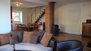 A living room with a sofa, a fireplace, a staircase, and a dining area.