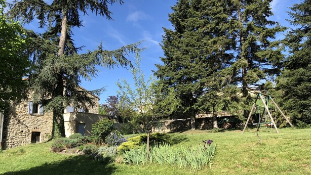 A stone building with a garden and a swing set.
