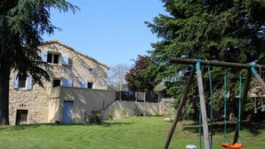 A stone building with a grassy yard and a swing set.