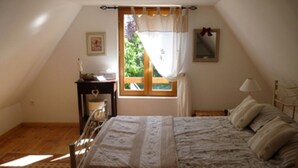 A bedroom with a bed, a nightstand, a window with curtains, a bedside table, and a mirror on the wall. - Character cottage with all the charm of the countryside (Anglars-Saint-Félix)