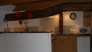 A kitchen with wooden cabinets, a microwave, a toaster, and a clock on the wall. - Character cottage with all the charm of the countryside (Anglars-Saint-Félix)