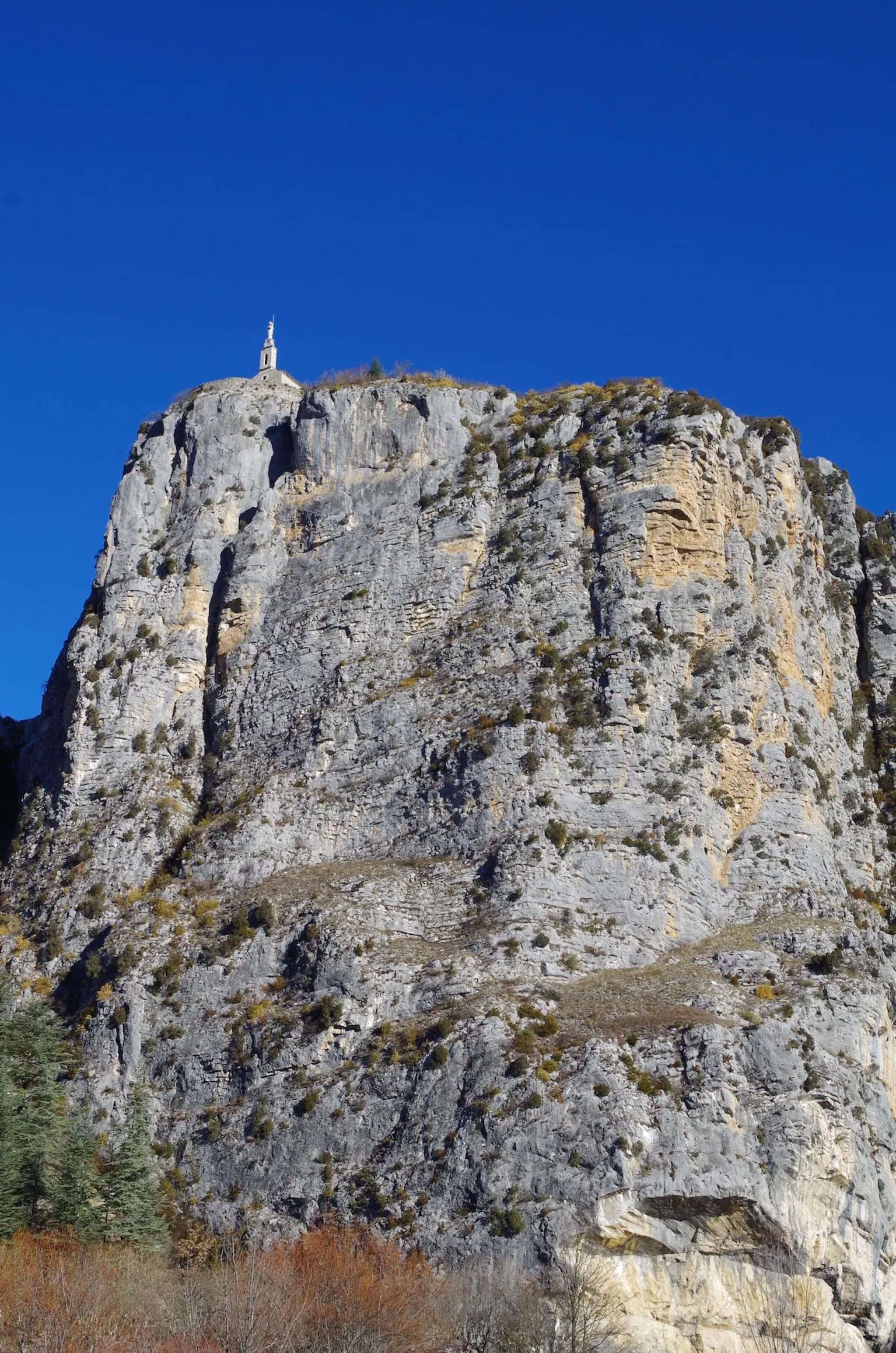 A rocky mountain with a small building on top.