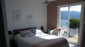 Una camera da letto con un letto, una sedia, un comodino e vista sull'esterno.