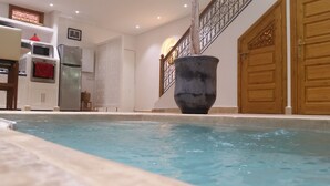 A swimming pool with a large decorative pot, a kitchen with modern appliances, and a wooden door with intricate carvings. - Riad Melilo heated swimming pool 2 steps from Jeema el Fna square (Marrakech)