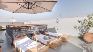 A rooftop terrace with a large umbrella, outdoor seating, a decorative fence, and a potted plant. - Riad Melilo heated swimming pool 2 steps from Jeema el Fna square (Marrakech)