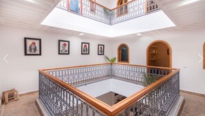 A multi-level atrium with a central open space, decorative railings, and framed artwork on the walls. - Riad Melilo heated swimming pool 2 steps from Jeema el Fna square (Marrakech)