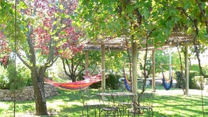 Un patio abrité avec un hamac, des chaises en métal et une table.