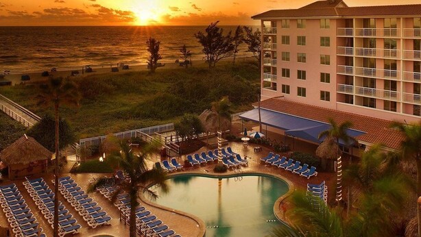 A resort with a pool, sun loungers, and a view of the ocean at sunset. - Palm Beach Shores Ocean Front Resort, Singer Island One Bedroom ~ Valet Parking (Palm Beach Shores)