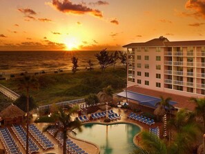 A resort with a pool, sun loungers, and a view of the ocean at sunset. - Palm Beach Shores Ocean Front Resort, Singer Island One Bedroom ~ Valet Parking (Palm Beach Shores)
