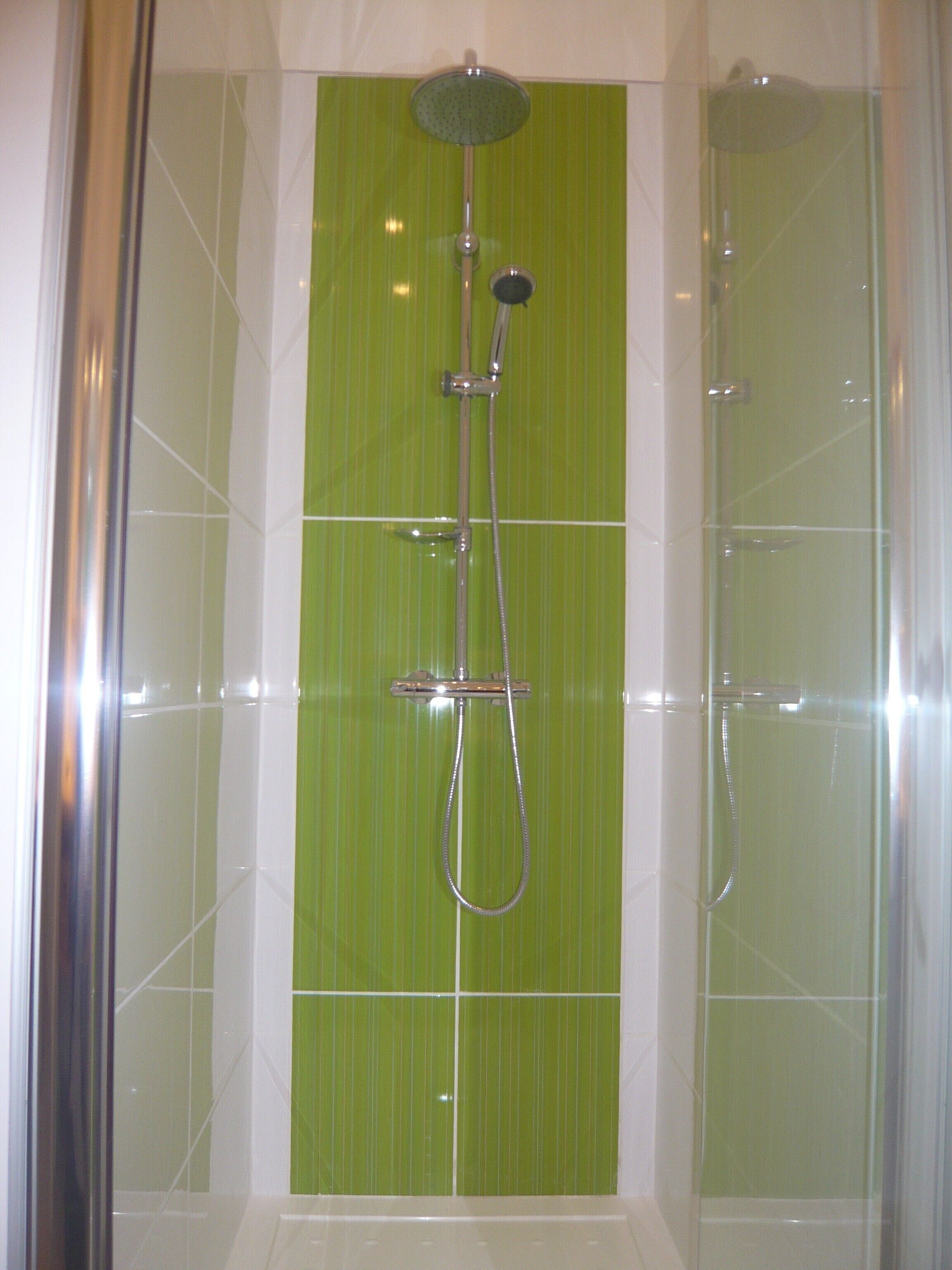 A shower with a rain showerhead, handheld showerhead, and a handheld hose.