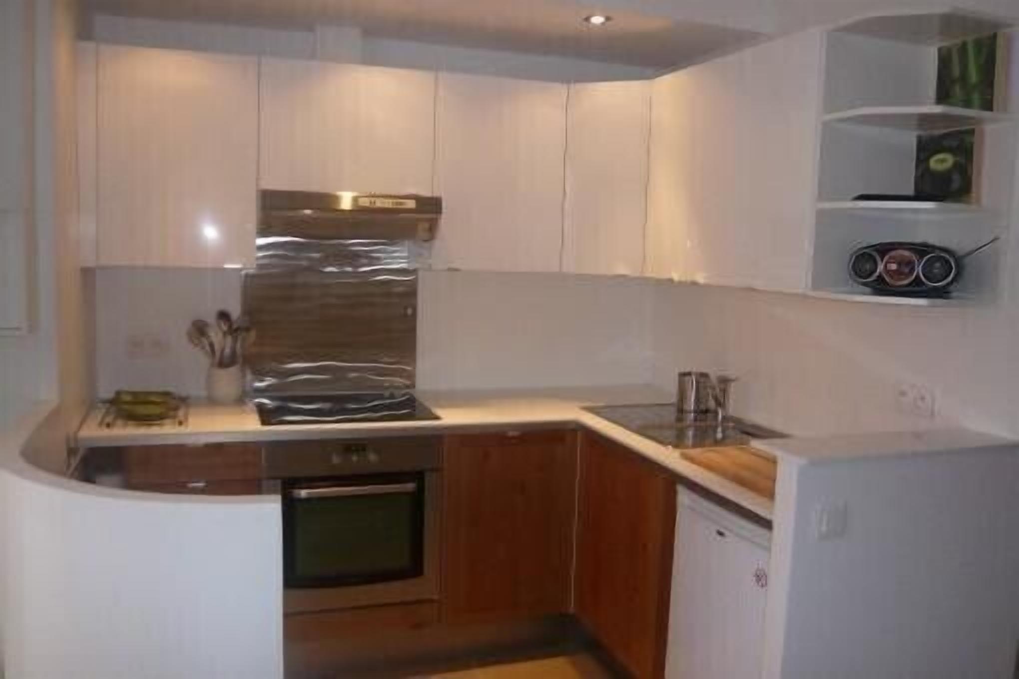 A compact kitchen with white cabinets, a stainless steel refrigerator, and a microwave.