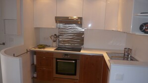 A compact kitchen with white cabinets, a stainless steel range hood, a built-in oven, and a small sink. - MENTON, 2 STEPS FROM THE SEA, CITY CENTER, STUDIO 2 ROOMS, QUALITY BENEFITS (Menton)