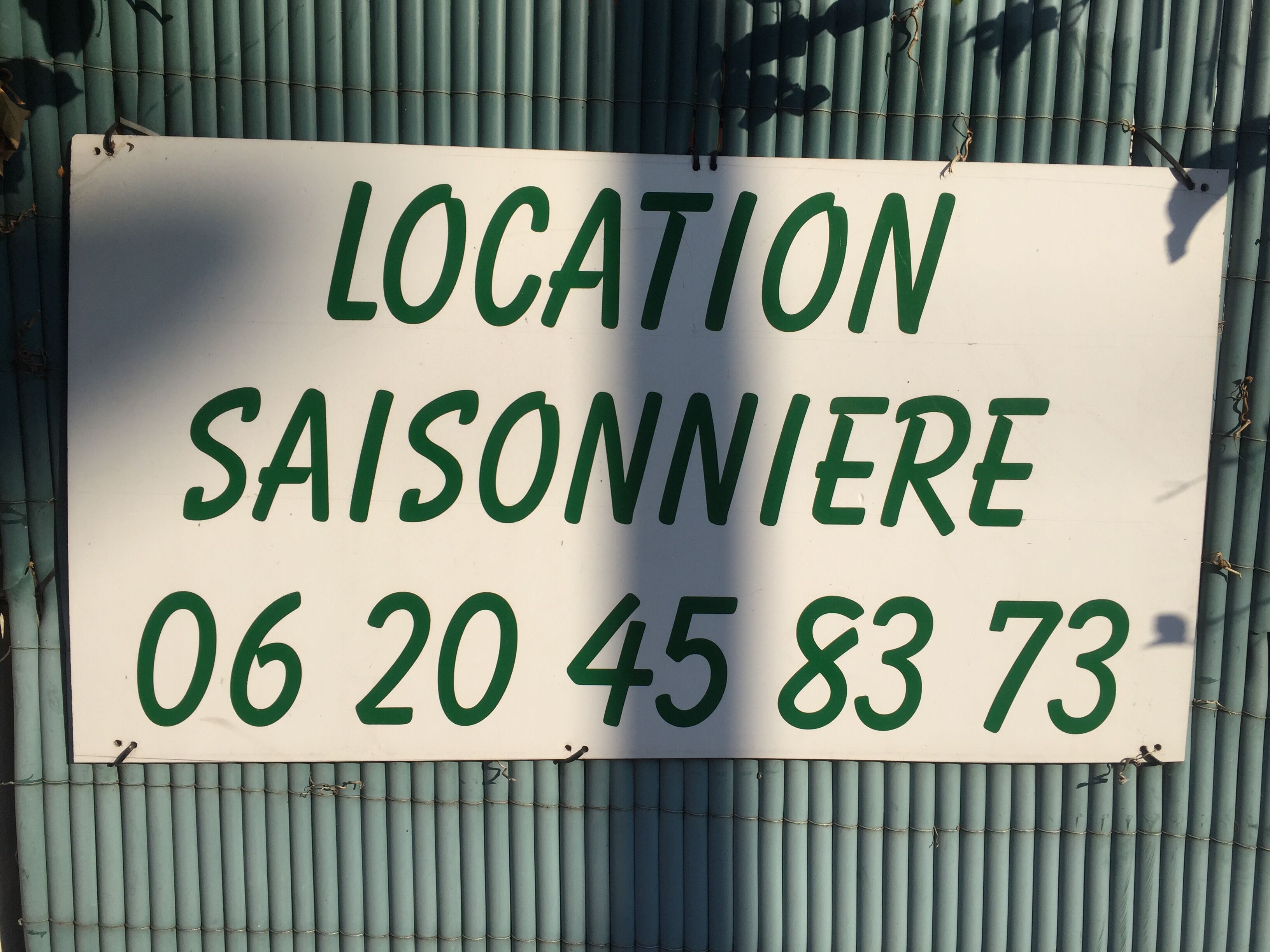 Une pancarte indiquant « LOCATION SAISONNIÈRE » et portant le numéro de téléphone « 06 20 45 83 73 ».