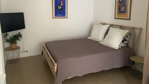 A bedroom with a bed, a TV, and two posters on the wall. - MENTON, 2 STEPS FROM THE SEA, CITY CENTER, STUDIO 2 ROOMS, QUALITY BENEFITS (Menton)
