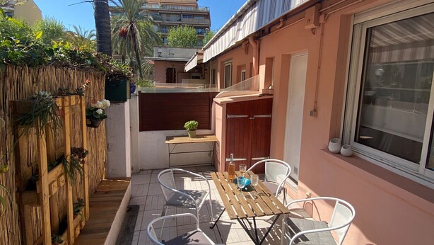 A patio with a table and chairs, a wooden fence, and a building with a window. - MENTON, 2 STEPS FROM THE SEA, CITY CENTER, STUDIO 2 ROOMS, QUALITY BENEFITS (Menton)