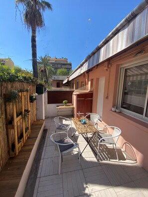 A patio with a table and chairs, a wooden fence, and a building with a window. - MENTON, 2 STEPS FROM THE SEA, CITY CENTER, STUDIO 2 ROOMS, QUALITY BENEFITS (Menton)