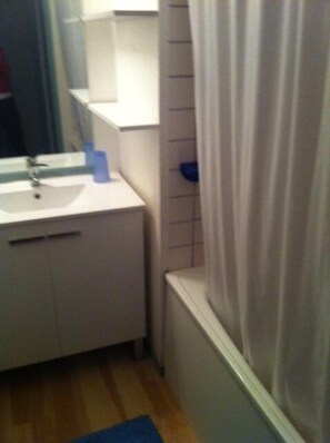 Une salle de bain avec un lavabo blanc, un miroir et un rideau de douche.