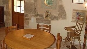 A rustic dining area with a round wooden table and chairs, stone walls, and a wooden ceiling. - COTTAGE *** with pool near Sarlat, Dordogne Périgord Noir (Prats-De-Carlux)