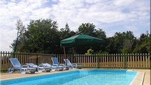 A swimming pool with lounge chairs and a green umbrella. - COTTAGE *** with pool near Sarlat, Dordogne Périgord Noir (Prats-De-Carlux)