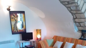 Une pièce confortable avec deux lits, une télévision, une lampe et un mur en pierre.