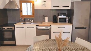 Una cocina moderna con una campana extractora de acero inoxidable, un microondas, un lavavajillas y un refrigerador.