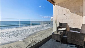 A balcony with wicker furniture overlooking a beach.