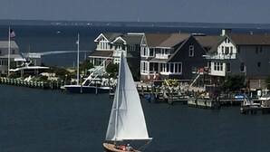 A sailboat on a calm body of water with houses in the background. - Bayfront with dock and fire pit, @ Harris Harbor, Beach  Haven Park, LBI (Long Beach Township)