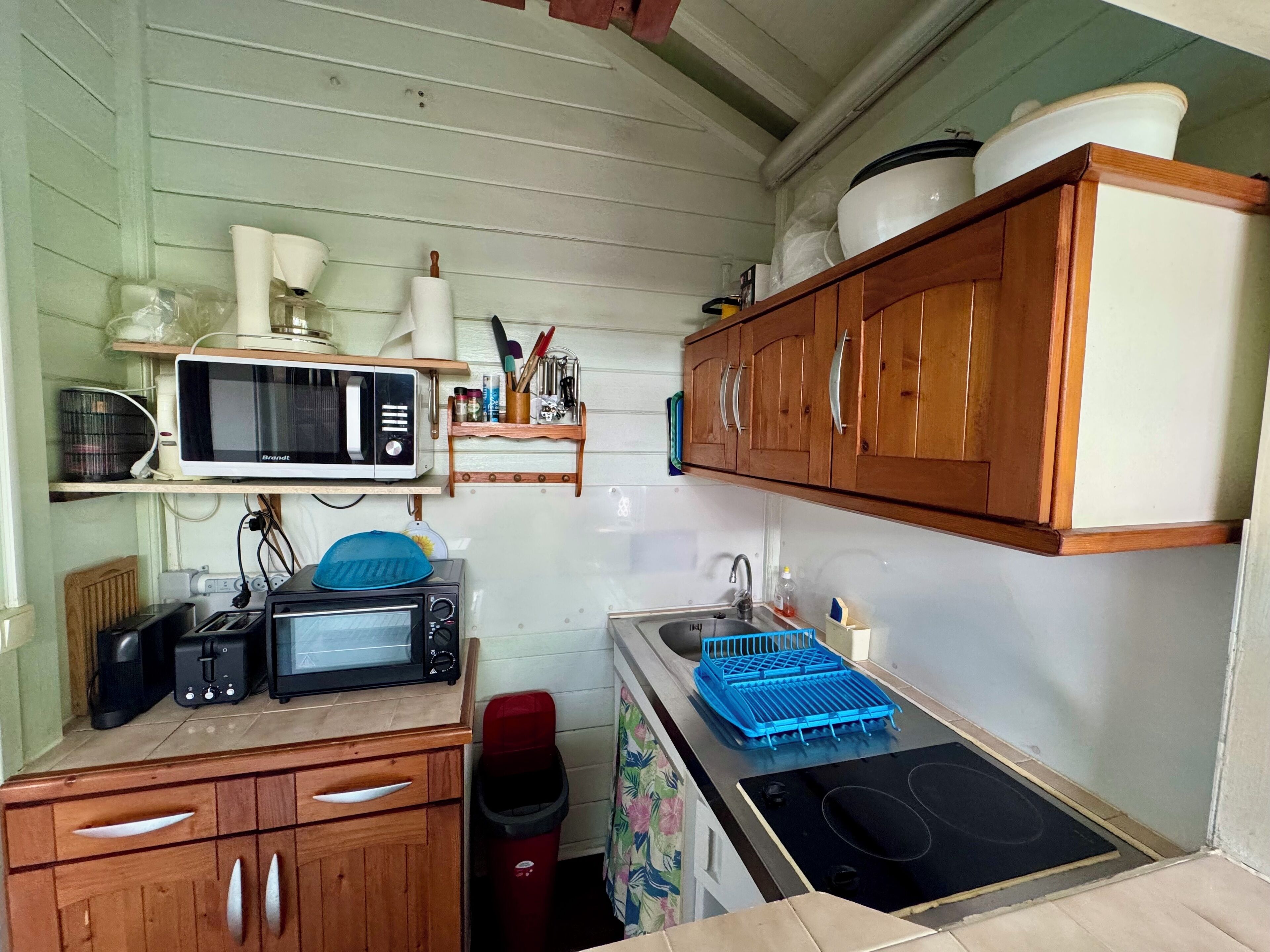 A compact kitchen with wooden cabinets, a microwave, a toaster, and a sink.