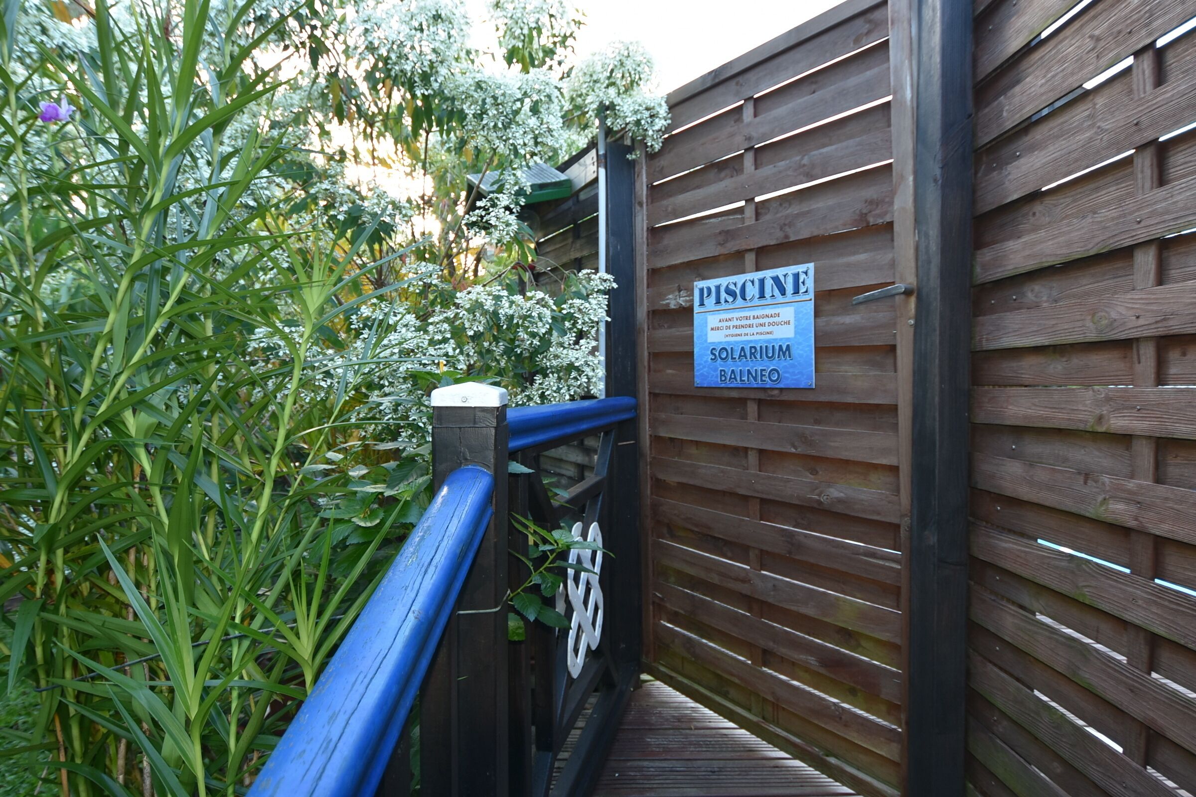 Ein Holzzaun mit einem Schild, auf dem 'PISCINE SOLARIUM BALNEO' steht.