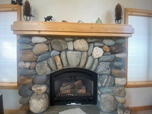 A stone fireplace with a wooden mantel, surrounded by a stone wall.