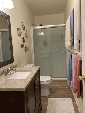 A bathroom with two sinks, a toilet, a glass shower enclosure, and a towel rack with multiple towels. - EMERALD ISLE - GREAT LOCATION! BEAUTIFUL VIEWS! 2nd Row, 4 BR, 2BA, SLEEPS 10 (Emerald Isle)