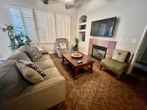 A living room with a sofa, armchair, coffee table, and a fireplace.