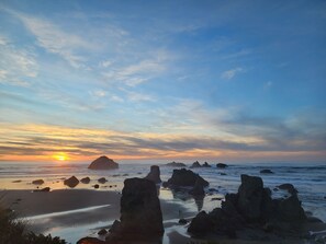 Un paisaje costero con formaciones rocosas destacadas y una puesta de sol sobre el océano.