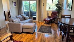 Un salon comprenant un canapé, un fauteuil en cuir rouge, une table à manger et un tapis.