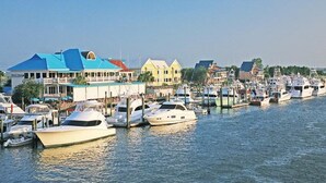 A marina with multiple yachts docked, a waterfront restaurant, and colorful buildings along the shore. - Beautiful 2nd floor unit with ocean views and 2 minute walk to the beach. (Wrightsville Beach)