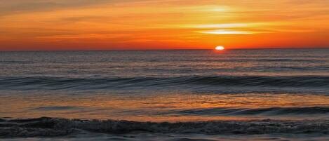 A sunset over the ocean with waves.