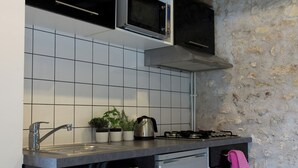 A compact kitchen with a microwave, stove, sink, and a small refrigerator. - Charming Cottage Set In The Loire Valley Just Minutes From Sancerre (Feux)