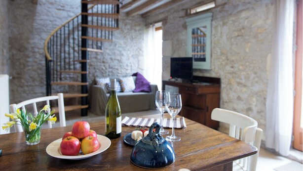 A dining area with a wooden table, a plate of apples, a bottle of wine, and a teapot. - Charming Cottage Set In The Loire Valley Just Minutes From Sancerre (Feux)