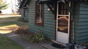 A small, single-story house with a gabled roof and a front porch. - Cozy one bedroom Hideaway Resort cabin #6 (Chippewa Falls)